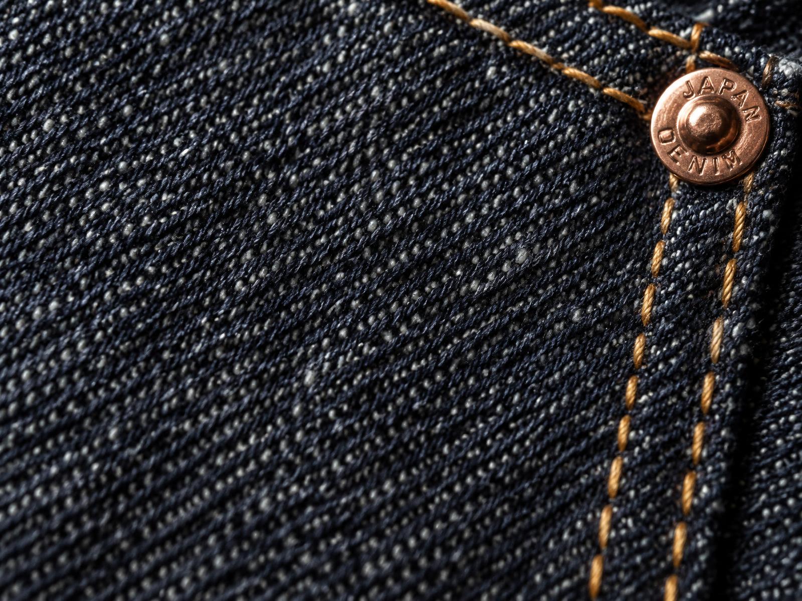Macro of raw Nihon Menpu 13oz indigo denim with copper rivet